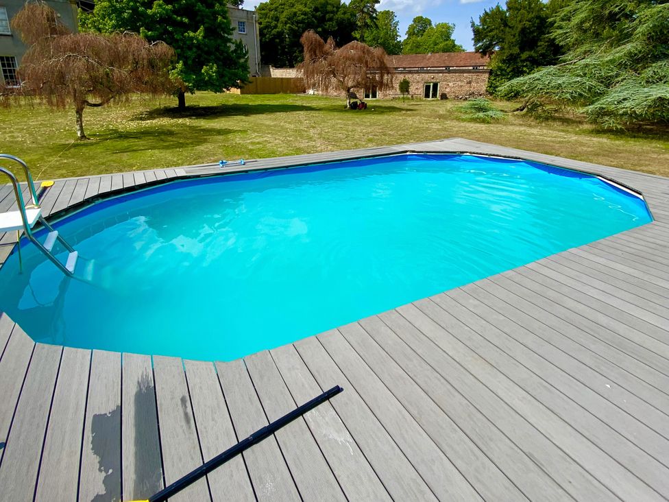 A swimming pool with decking and trees at Frenchay Park House in Bristol