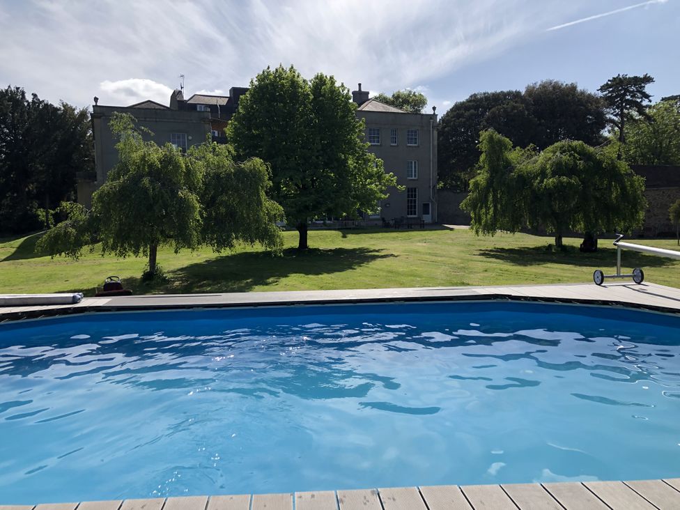 A pool overlooking a house and trees at Frenchay Park House in Bristol