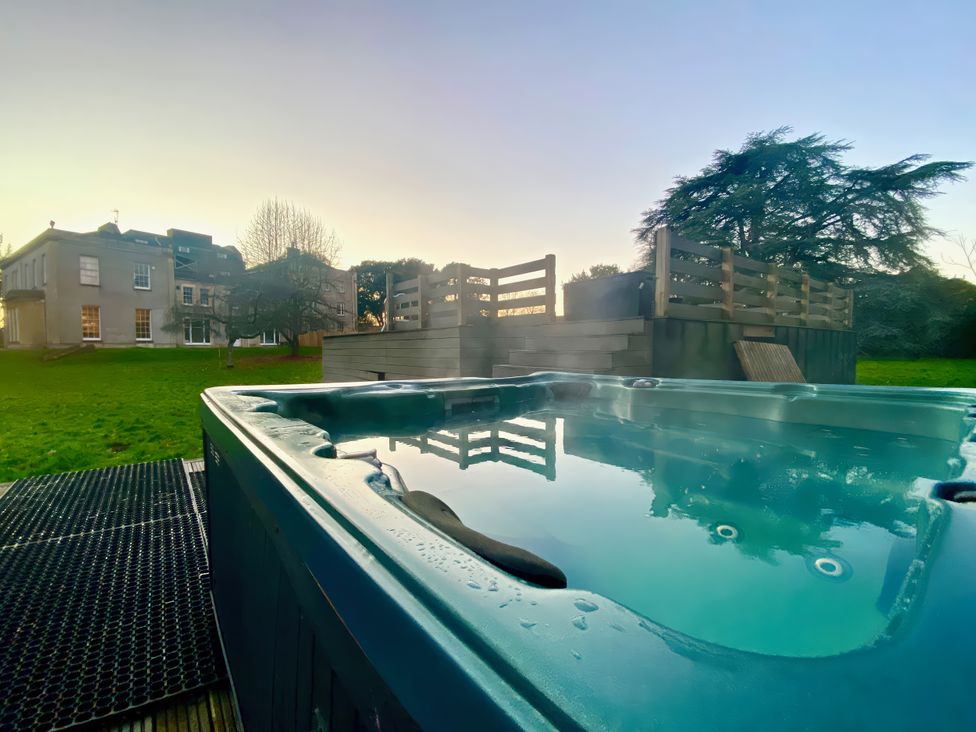 A hot tub with a view of a building and grass at Frenchay Park House Bristol