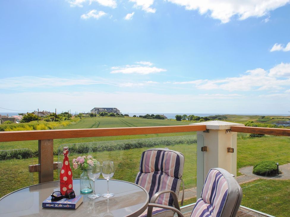 A terrace with a table and chairs overlooking a field at 8 Thurlestone Beach in Kingsbridge