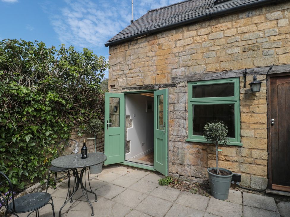 An outdoor area with a green door and table at Wheelwright Cottage in Moreton-In-Marsh