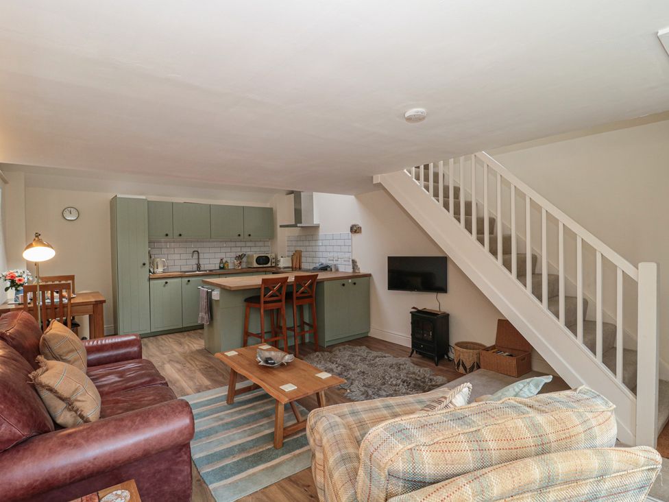 A living room with a kitchen area and staircase at Wheelwright Cottage in Moreton-In-Marsh