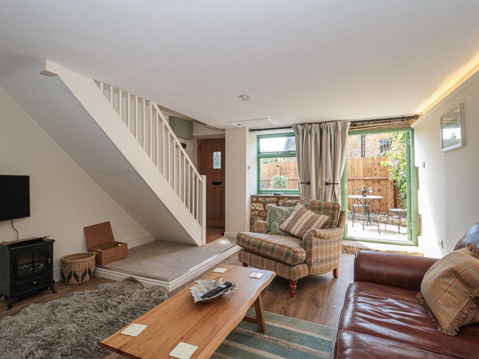 A living room with a staircase and a patio door at Wheelwright Cottage in Moreton-In-Marsh