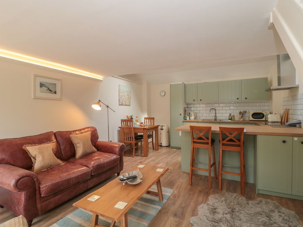 A kitchen and living area with furniture at Wheelwright Cottage in Moreton-In-Marsh
