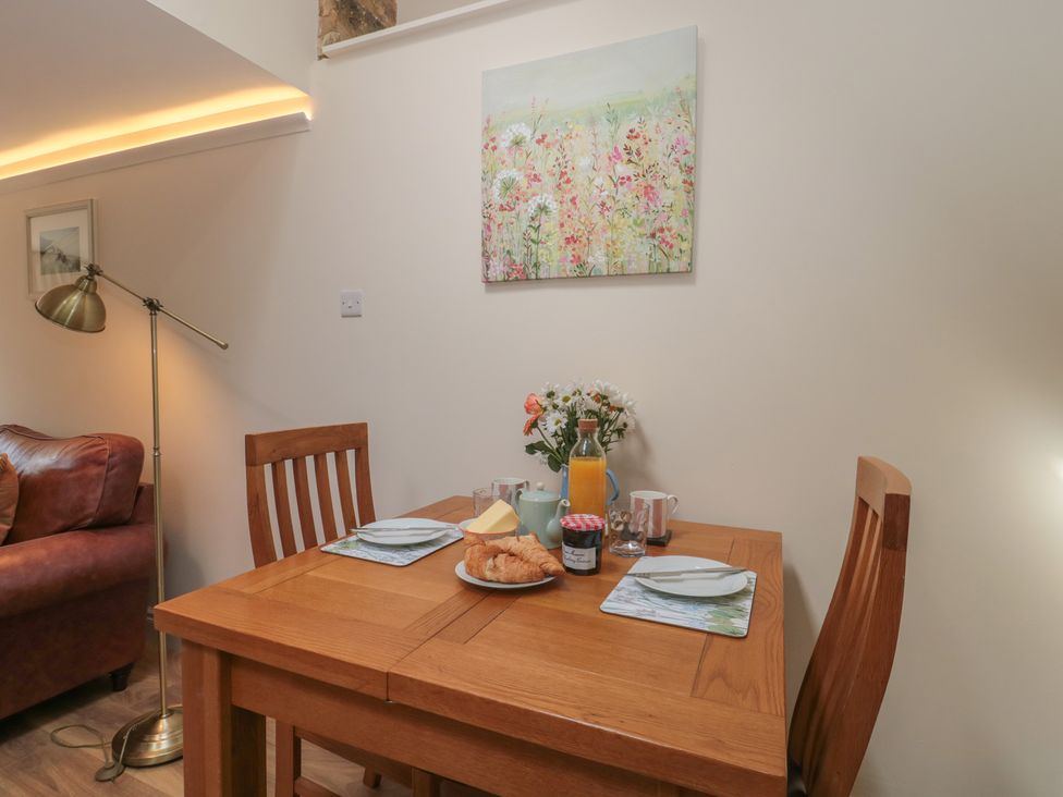 A dining room with a table set for breakfast at Wheelwright Cottage Moreton-In-Marsh