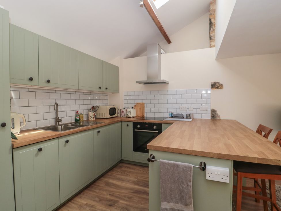 A kitchen with green cabinets and wooden countertop at Wheelwright Cottage in Moreton-In-Marsh