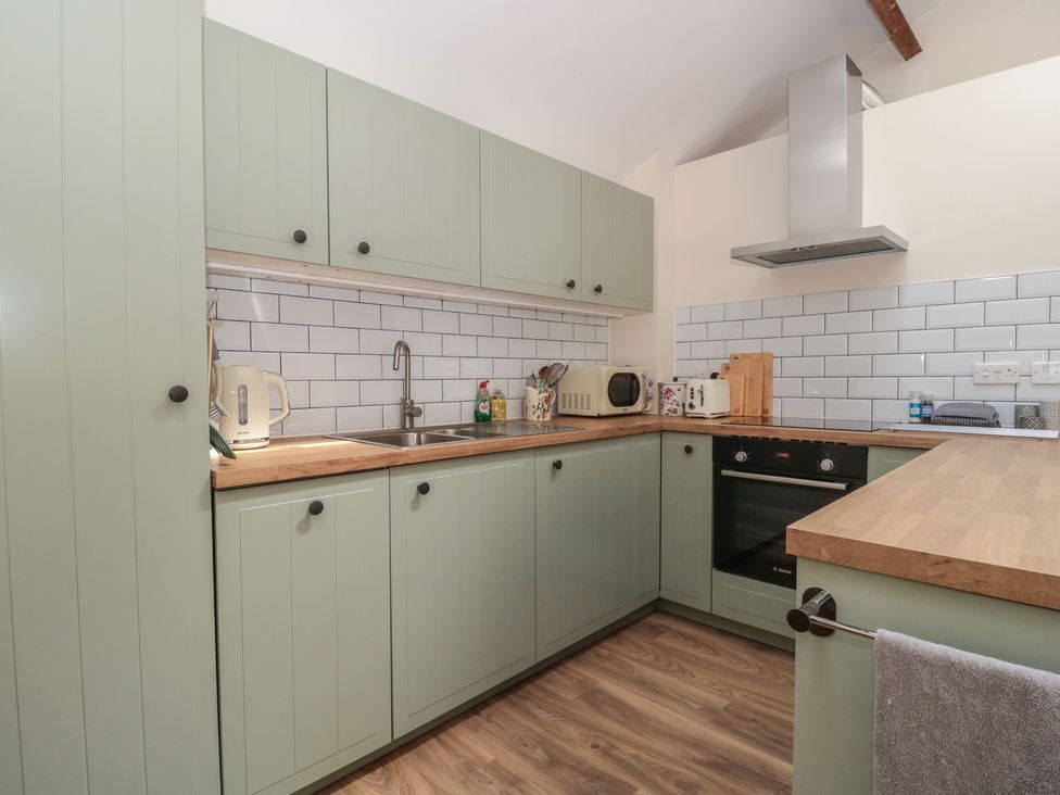 A kitchen with cabinets, sink, kettle, and oven at Wheelwright Cottage Moreton-In-Marsh