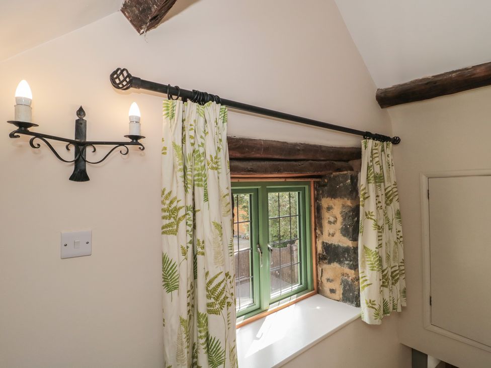 A window with curtains and a light fixture at Wheelwright Cottage in Moreton-In-Marsh