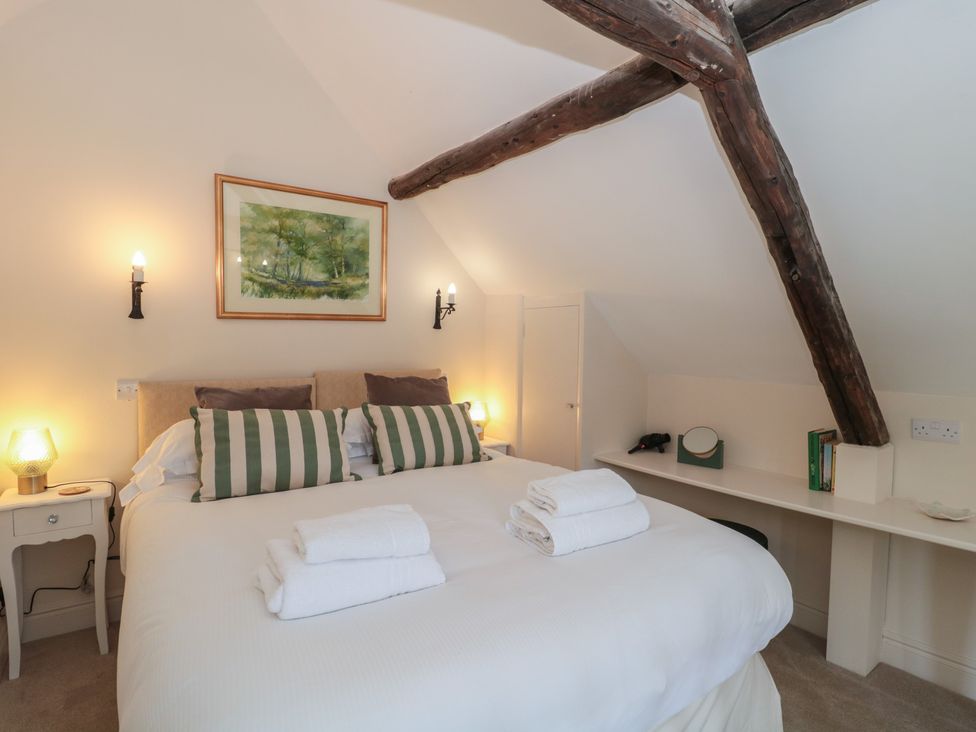 A bedroom with a bed and wall art at Wheelwright Cottage in Moreton-In-Marsh