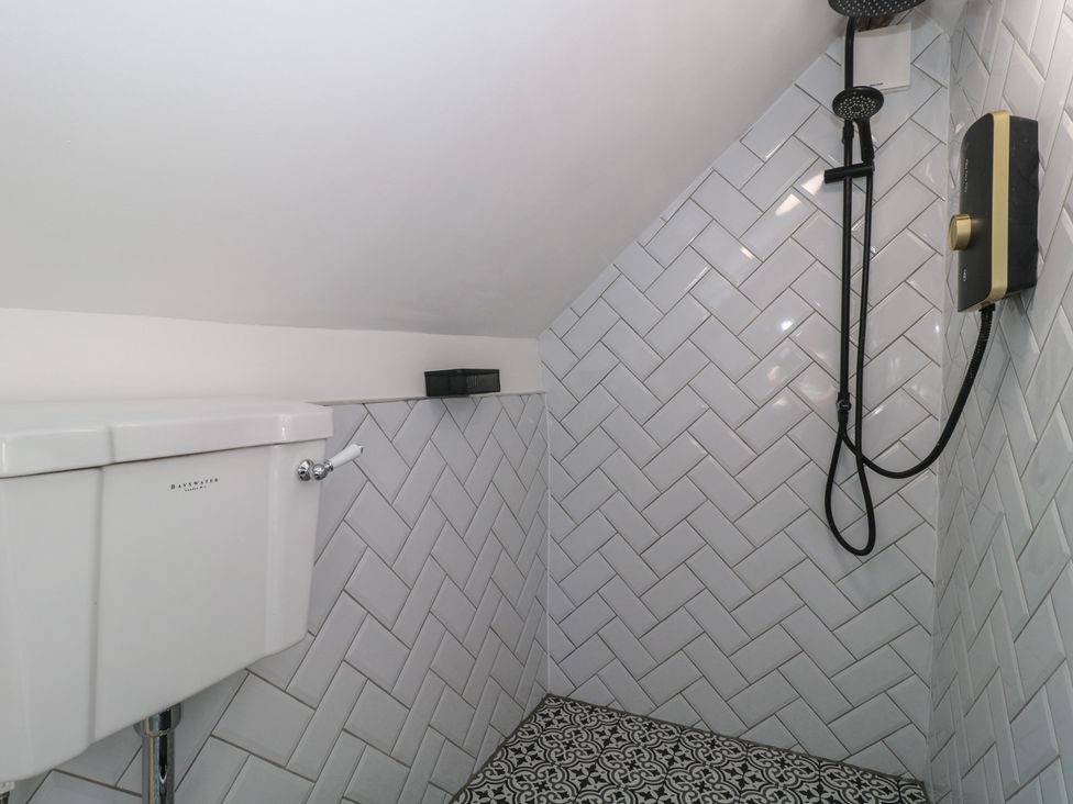 A bathroom with a toilet and shower at Wheelwright Cottage Moreton-In-Marsh