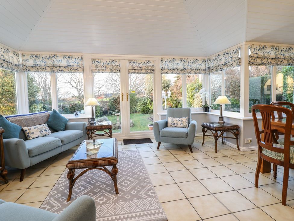 A conservatory with seating and garden view at Llwyn Derw Talybont