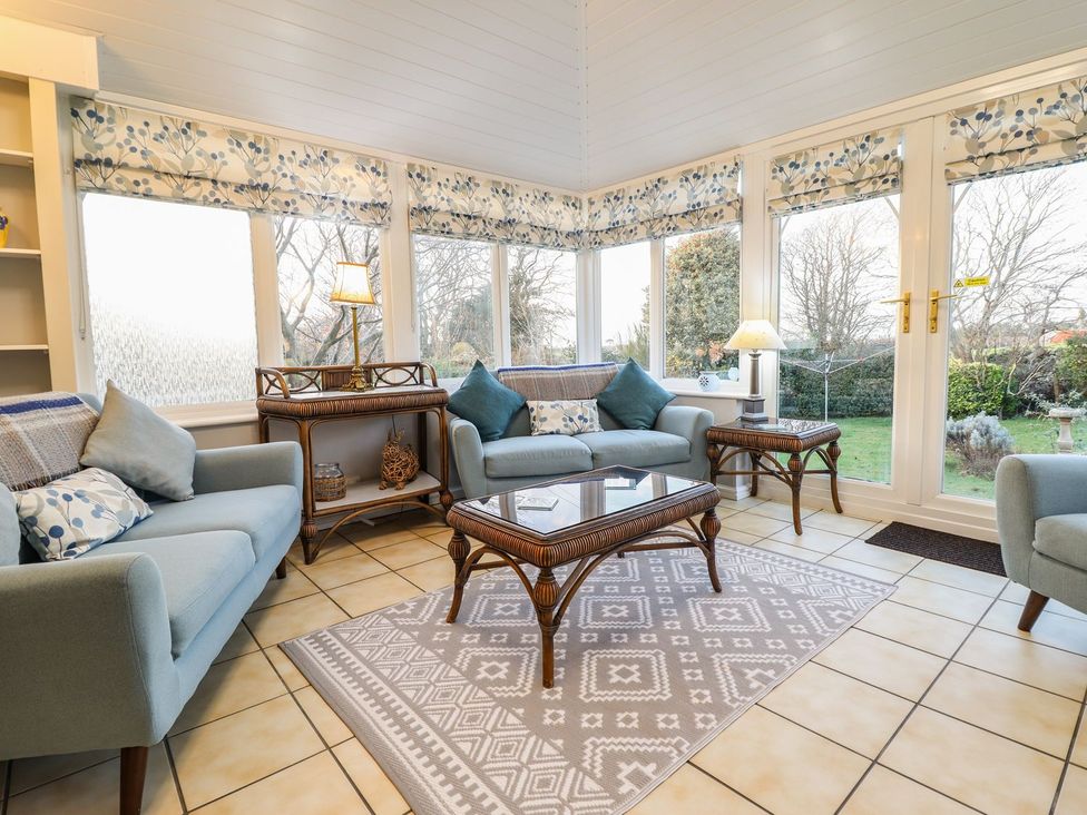 A conservatory with seating and a coffee table at Llwyn Derw in Talybont