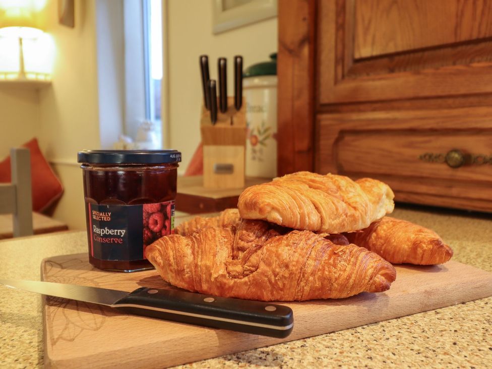 A kitchen with croissants and jam on a cutting board at Llwyn Derw Talybont