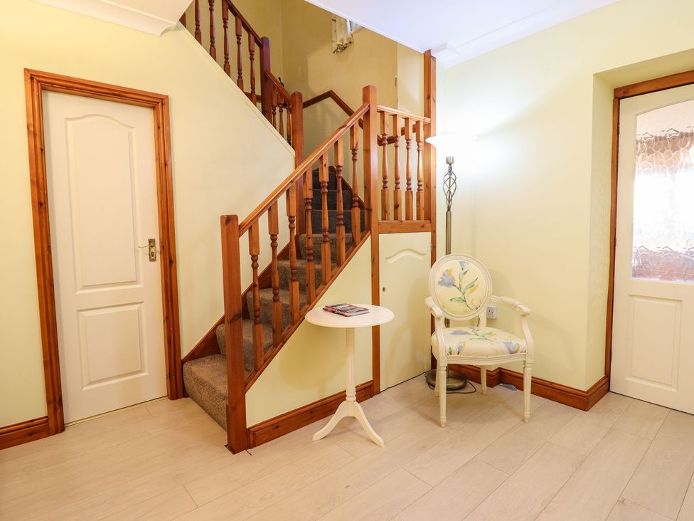 A hallway with a staircase and chair at Llwyn Derw in Talybont