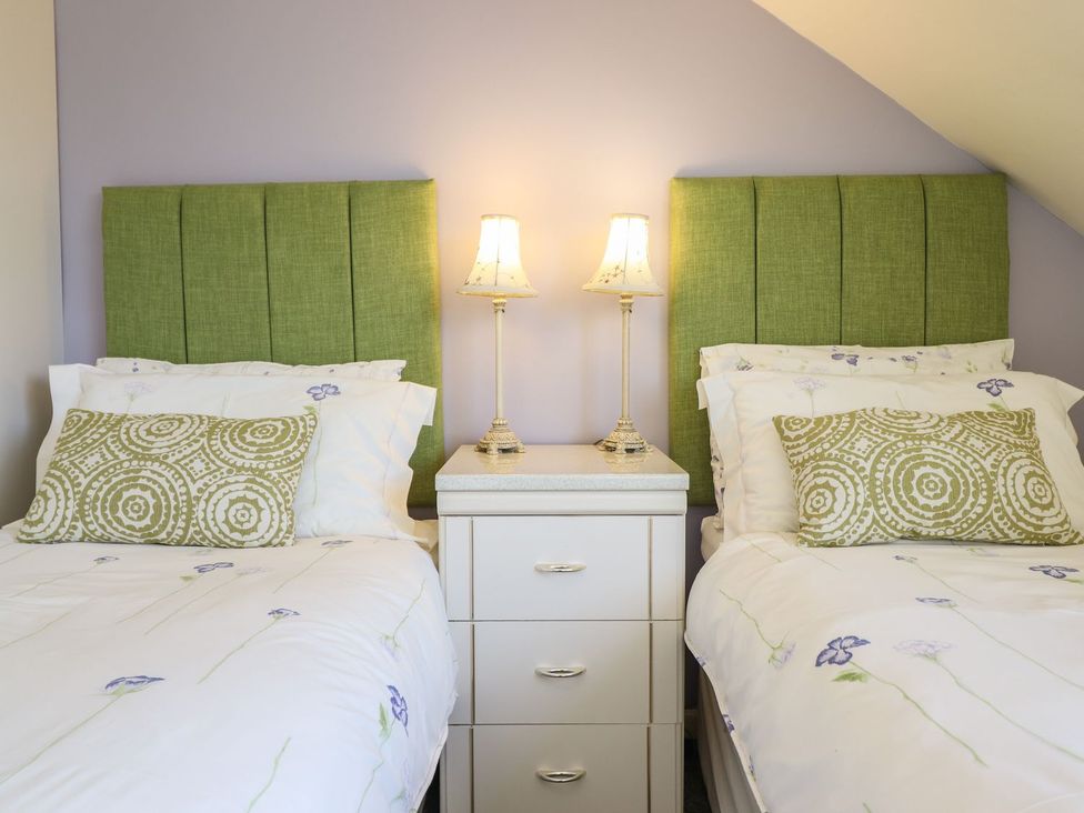 A bedroom with two beds and a nightstand at Llwyn Derw in Talybont