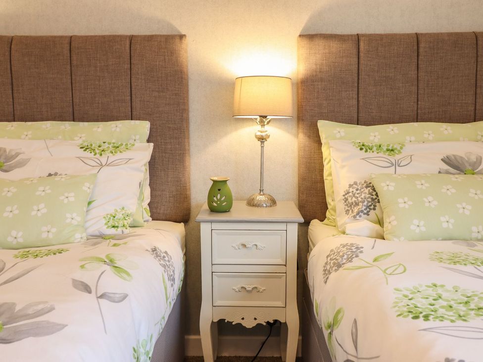 A bedroom with beds and bedside table at Llwyn Derw, Talybont
