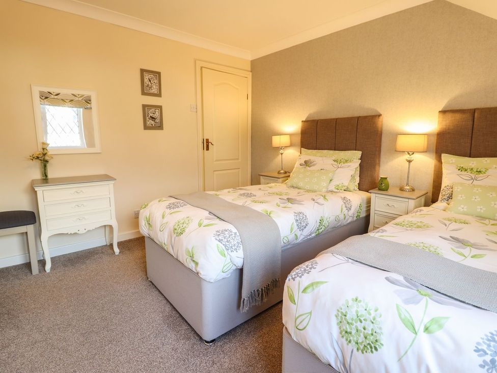 A bedroom with twin beds, bedside tables and a dresser at Llwyn Derw in Talybont