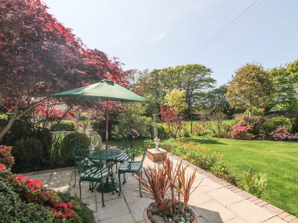 A garden with a table and chairs under an umbrella at Llwyn Derw Talybont