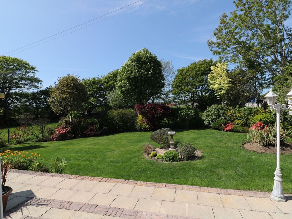 A garden with flower beds and a birdbath at Llwyn Derw in Talybont