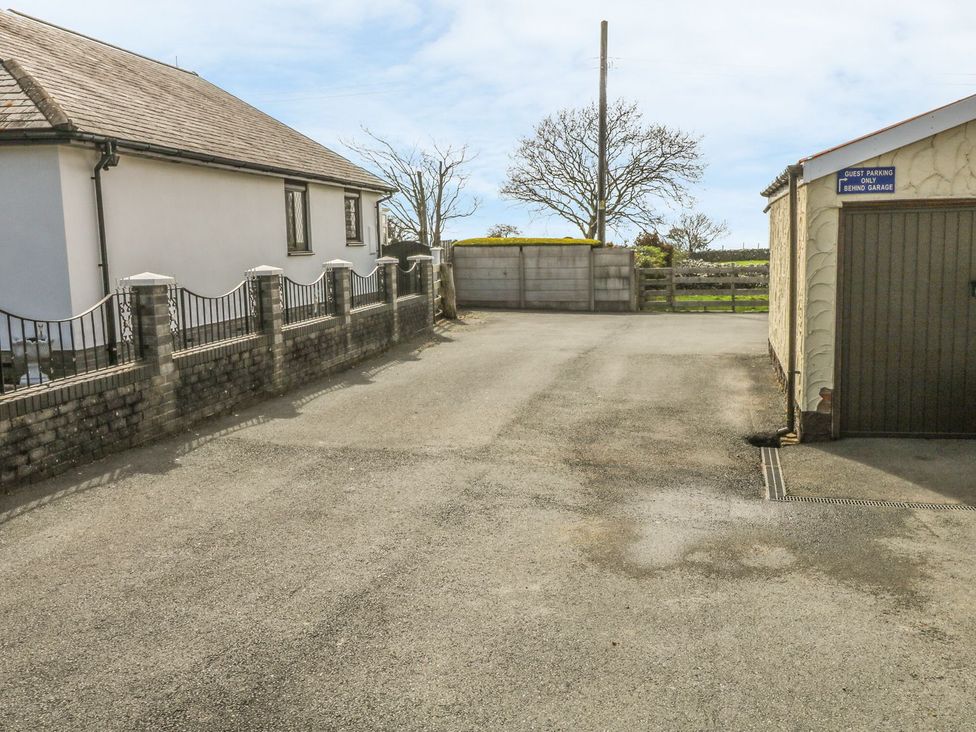An outdoor area with a house, wall, garage and trees at Llwyn Derw in Talybont