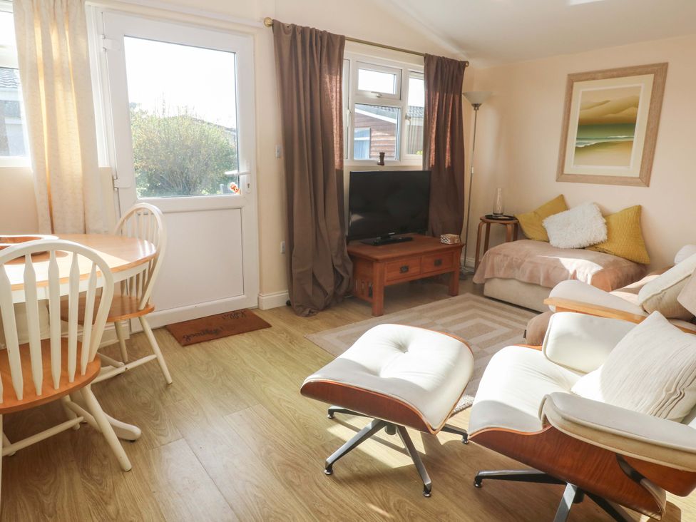 A living room with a sofa and dining area at Chalet 225 in Tregolds near St Merryn