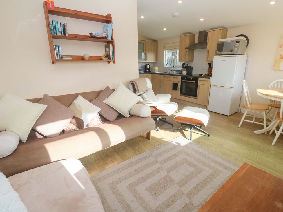 A living room with a sofa and kitchen area at Chalet 225 Tregolds near St Merryn