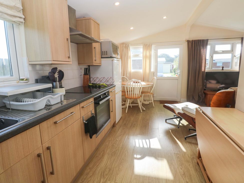 A kitchen with cabinets and a dining table at Chalet 225 Tregolds near St Merryn