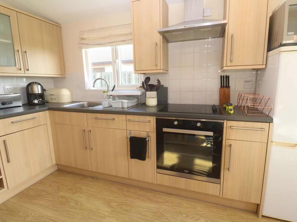 A kitchen with cabinets, sink, and appliances at Chalet 225 Tregolds near St Merryn