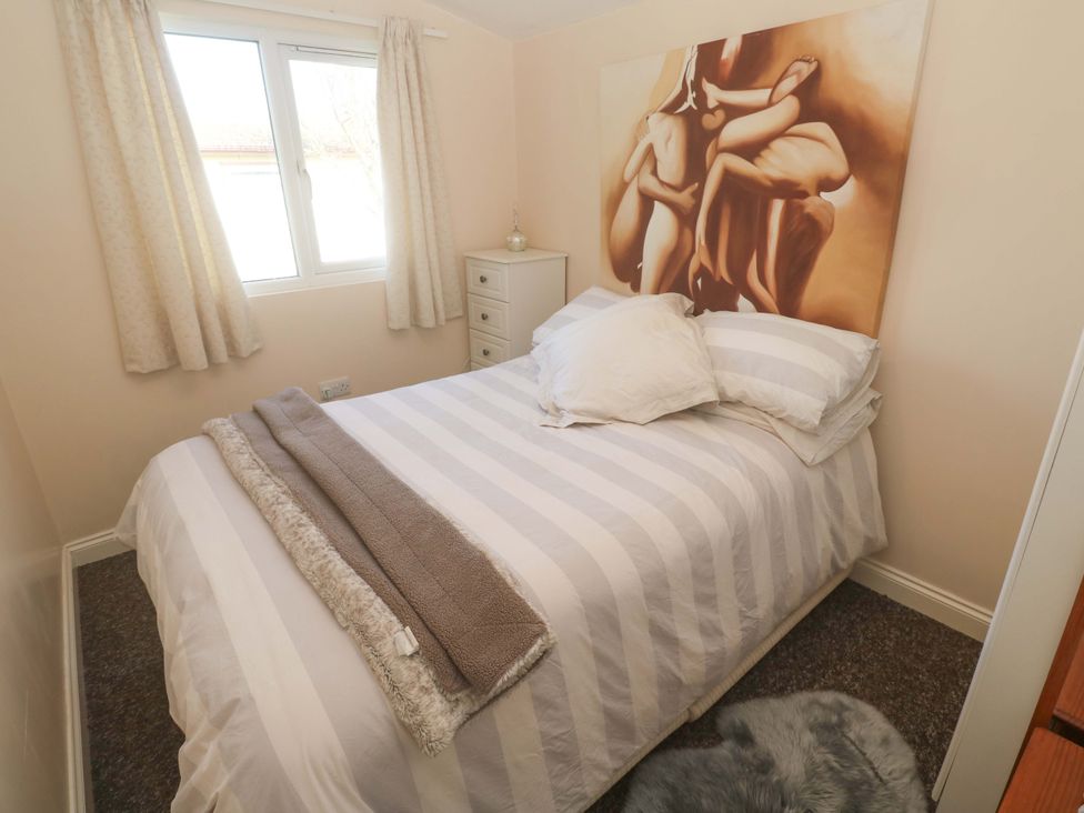 A bedroom with a bed and artwork at Chalet 225 Tregolds near St Merryn