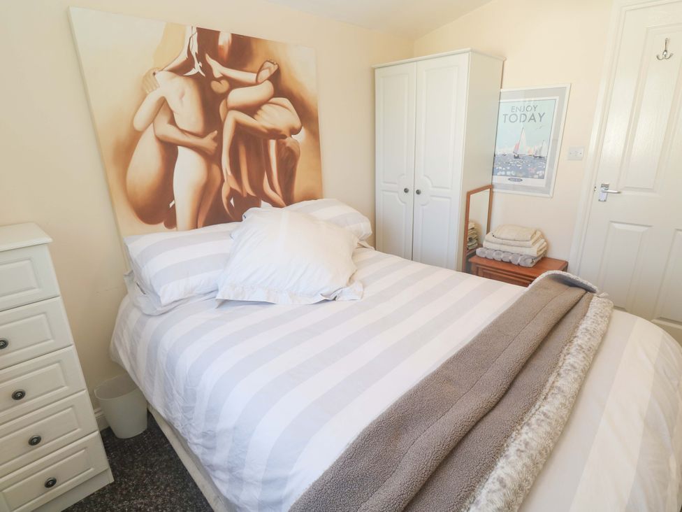 A bedroom with a striped bed and wardrobe at Chalet 225 Tregolds near St Merryn