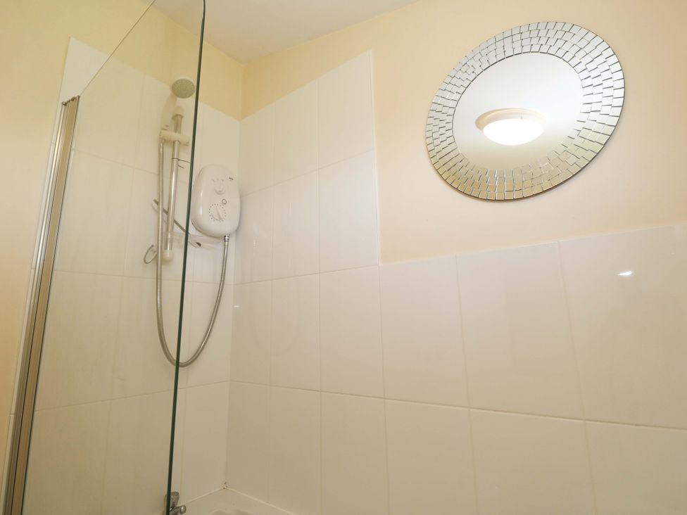 A shower area with a circular mirror at Chalet 225 Tregolds near St Merryn