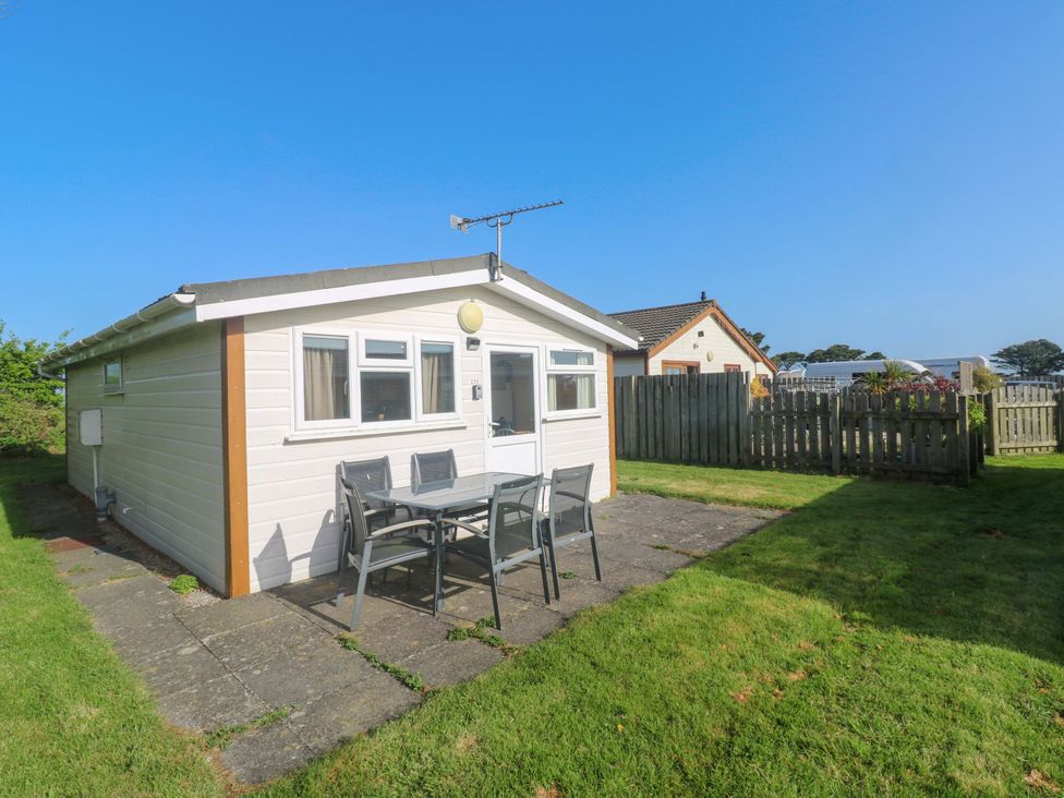 A garden with a cabin and patio furniture at Chalet 225 Tregolds near St Merryn
