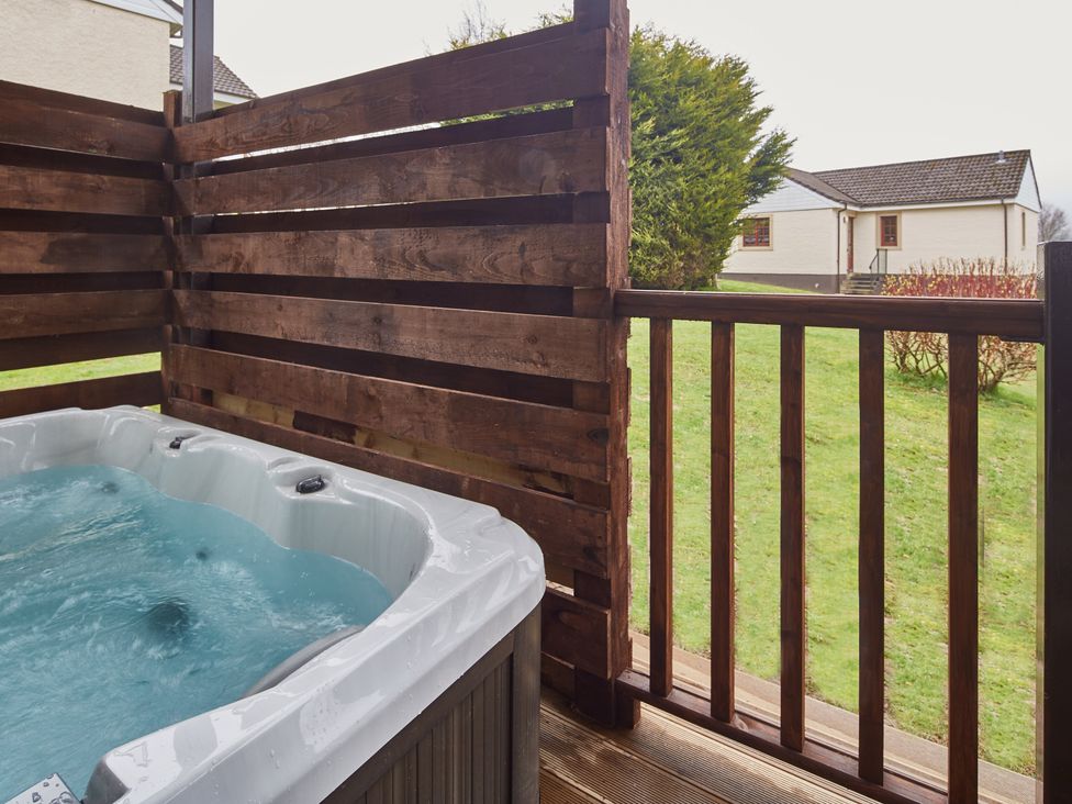 A hot tub on a deck with wooden fencing at Ailsa Craig Spa Dailly