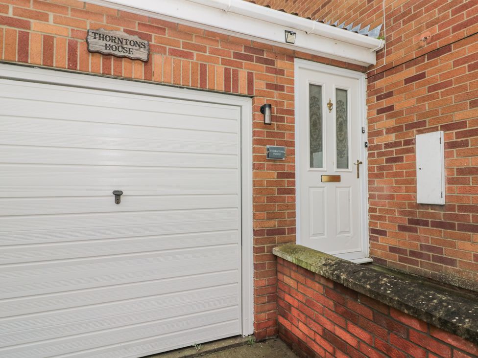 An exterior view of a garage door and front entrance at Thorntons House in Northallerton