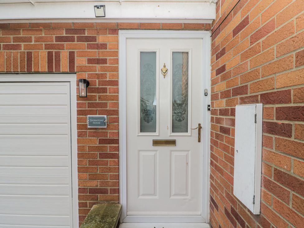 An entryway with a white door and brick wall at Thorntons House in Northallerton