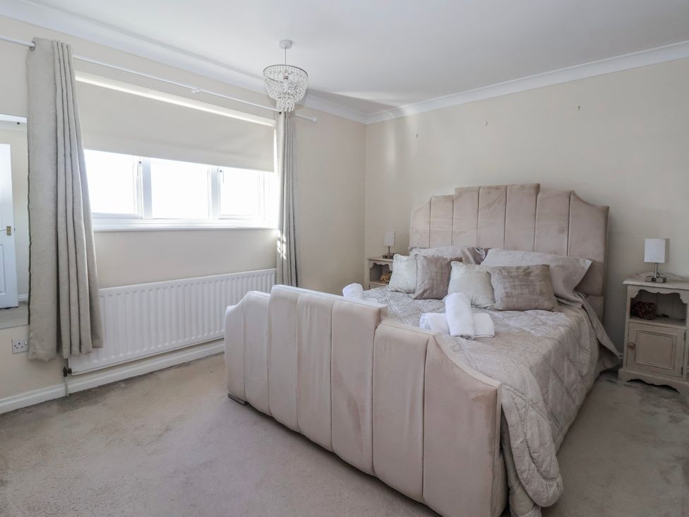 A bedroom with a bed, bedside tables, and a window at Thorntons House in Morton-On-Swale