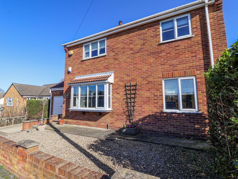 A brick house with a garden trellis and flower pots at Thorntons House Morton-On-Swale