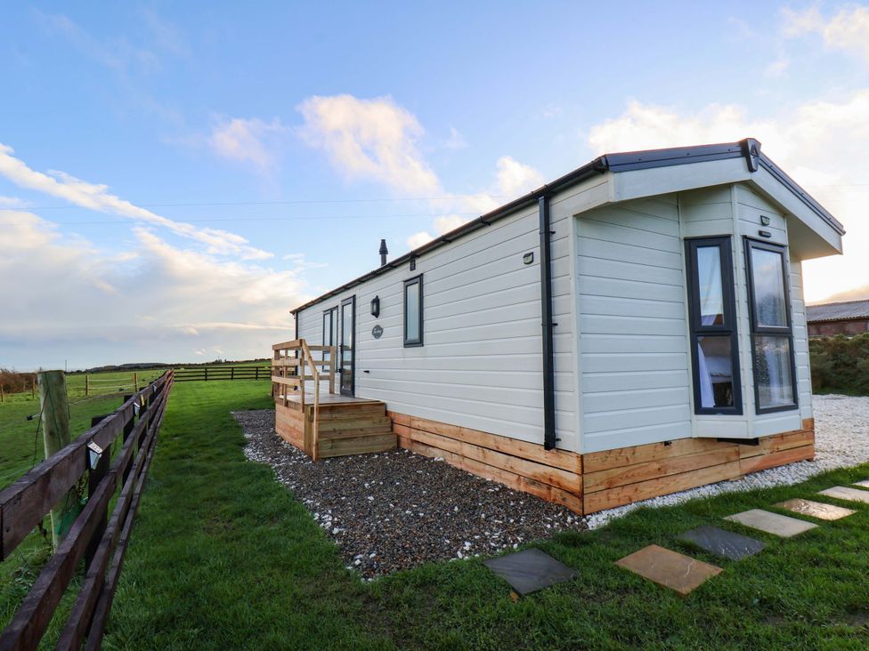 A cabin with a deck and grass area at Rosefinch Cabin Scarborough