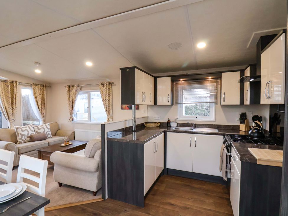 A kitchen with cabinets and a dining area at Rosefinch Cabin in Scarborough