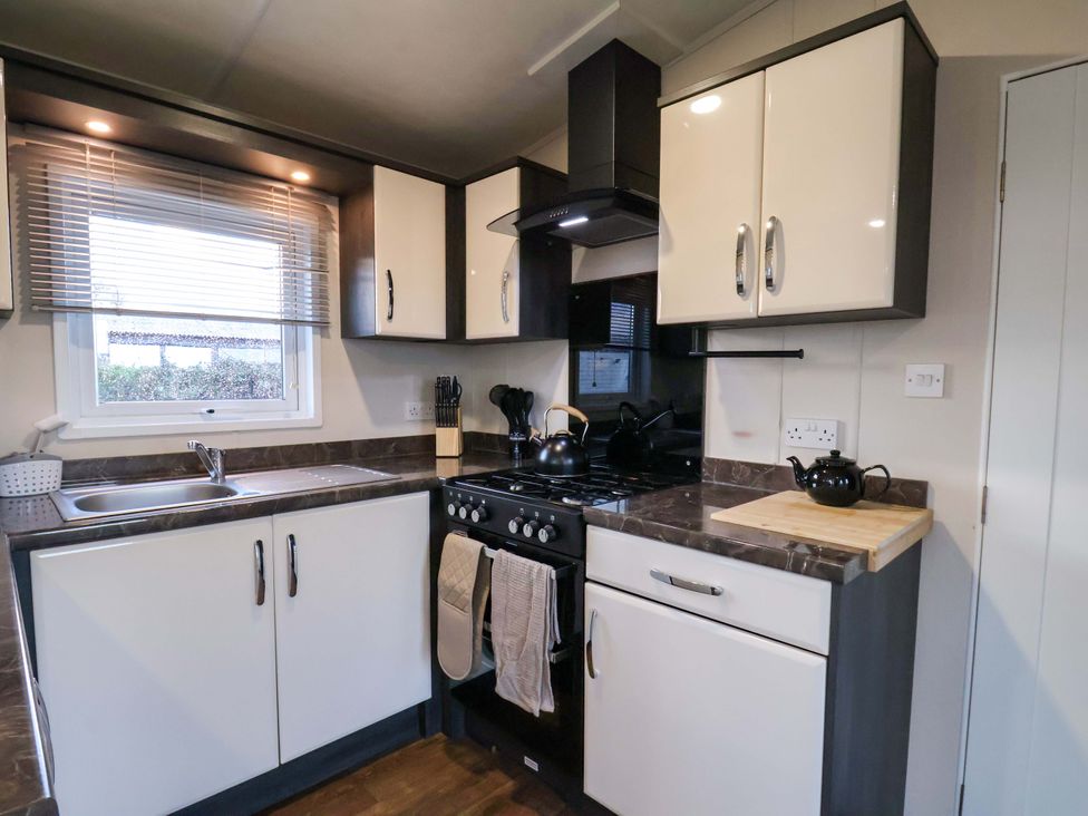 A kitchen with cabinets, sink, and stove at Rosefinch Cabin Scarborough