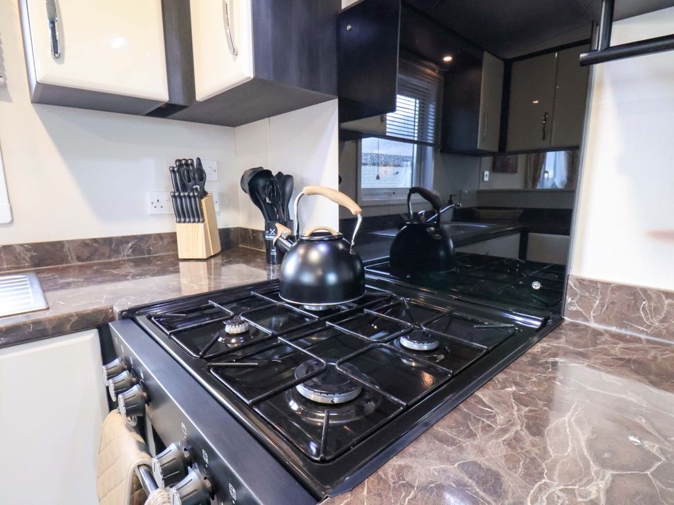 A kitchen featuring a gas stove and a kettle at Rosefinch Cabin in Scarborough