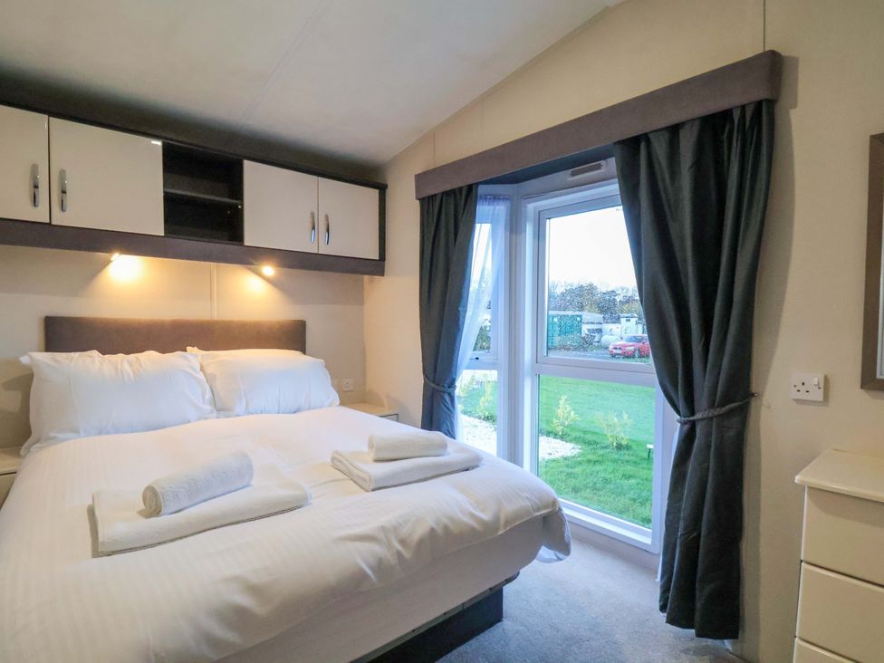 A bedroom with a bed and towels at Rosefinch Cabin in Scarborough