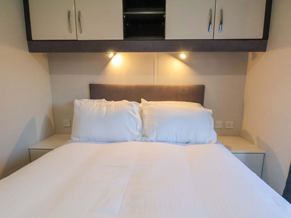 A bedroom with a bed and wall cabinets at Rosefinch Cabin in Scarborough