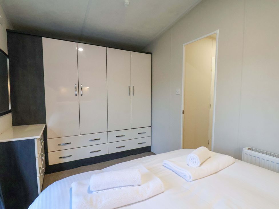 A bedroom with a bed and wardrobe at Rosefinch Cabin in Scarborough