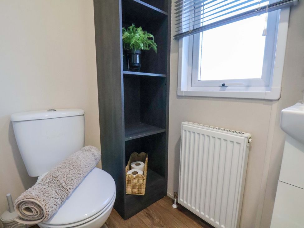 A bathroom with a toilet and a shelf at Rosefinch Cabin in Scarborough