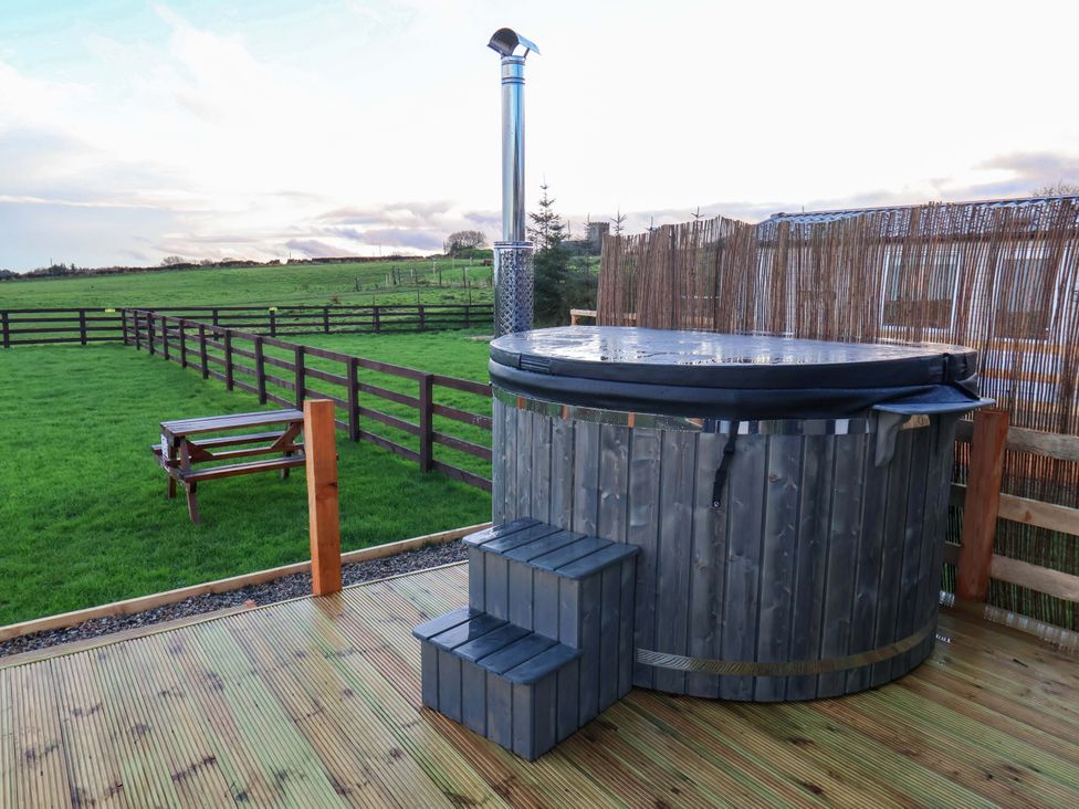 A hot tub with steps and stove in a grassy area at Rosefinch Cabin in Scarborough
