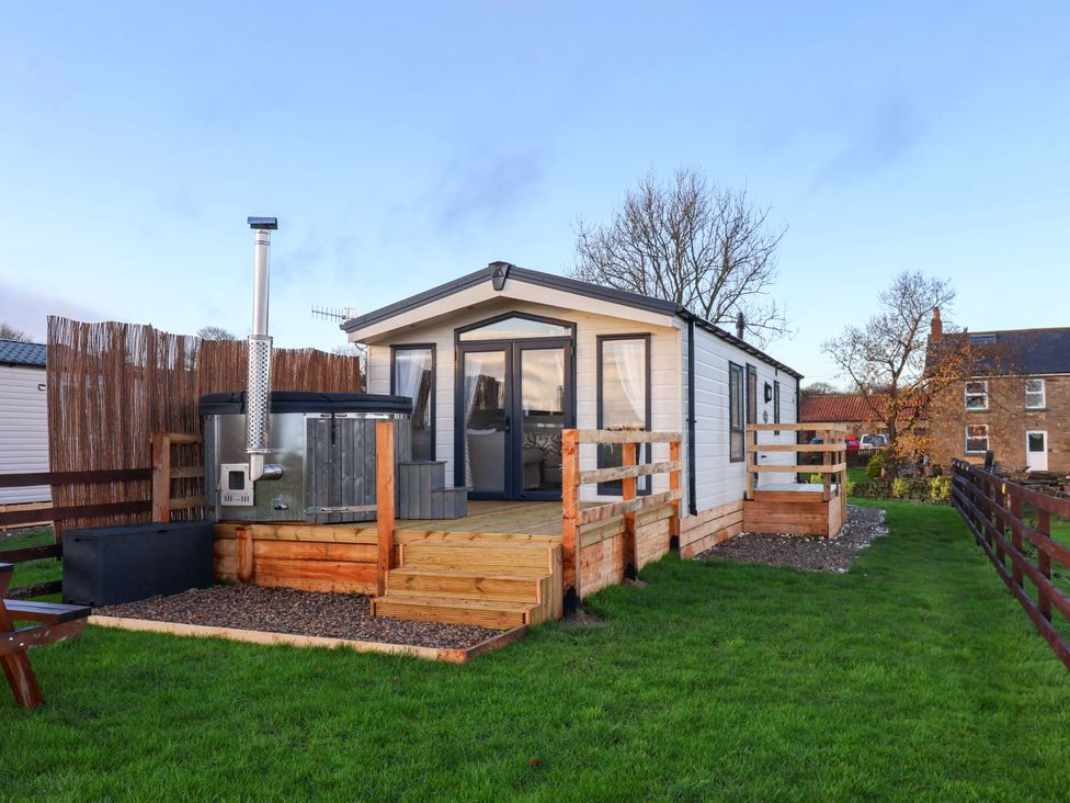 An outdoor area with a cabin and hot tub at Rosefinch Cabin in Scarborough