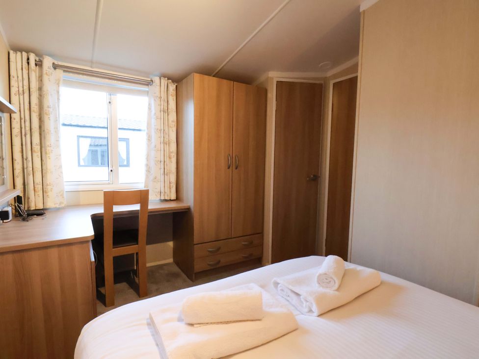 A bedroom with a bed and desk at Swift Cabin Scarborough