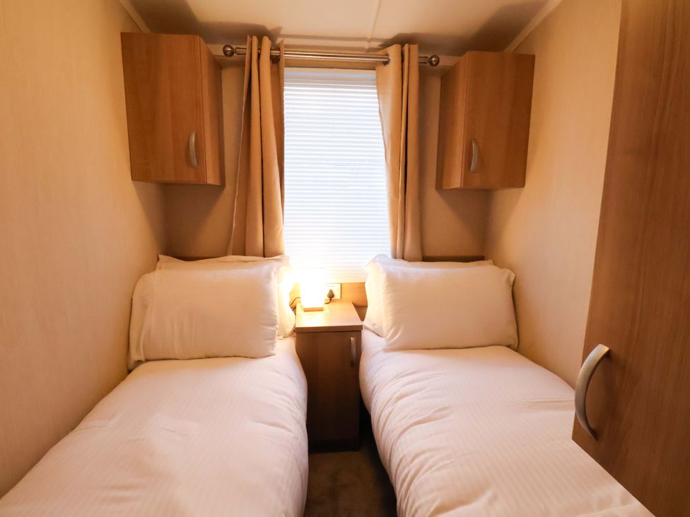 A bedroom with twin beds and a lamp at Swift Cabin in Scarborough