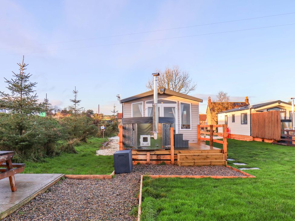 A cabin with outdoor seating and grass area at Swift Cabin Scarborough